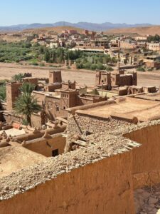 Explore the captivating architecture of a Moroccan village with lush greenery and desert backdrop.