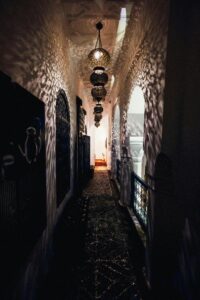 A dimly lit Moroccan corridor featuring traditional lanterns and ornate walls in Marrakech.